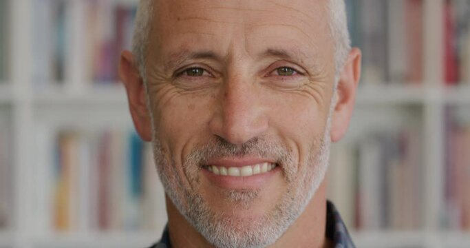 Close up portrait mature man smiling in fornt of bookshelf