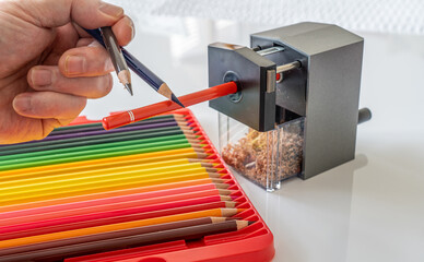 Sharpening a set of  professional artists quality colored oil wax based pencils in a rotary mechanical sharpener to a fine point - Powered by Adobe