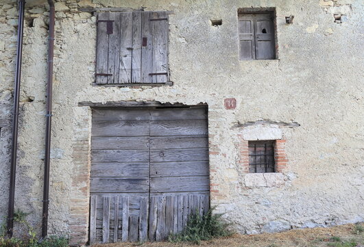 Old Stone Barn Facade with Closed Wooden Entrance and Windows in Italian Rural Village