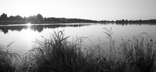 Black and white panoramic view of a sunrise over a small lake