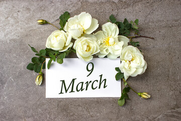 March 9th. Day 9 of month, Calendar date. White roses border on pastel grey background with...