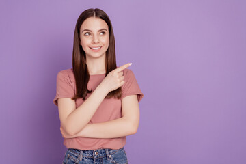 Happy young woman look empty space pointing way with fingers isolated over violet background