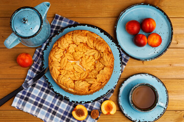 Homemade pie with nectarines and cup of tea on wooden table. Top view.