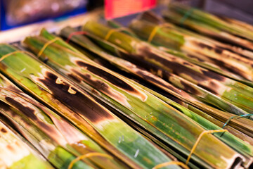 Kanom jak, or glutinous rice flour mixed with coconut and various fillings, is wrapped in leaves and then grilled over a flame. © Palakorn Jaiman