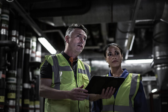 Male Engineer Training A Female Engineer In An Industrial Plant Room