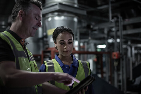 Male engineer training a female engineer in an industrial plant room