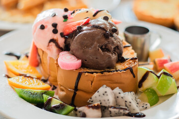 Honey Toast topped with ice cream and fresh fruit. and topped with chocolate sauce and honey.