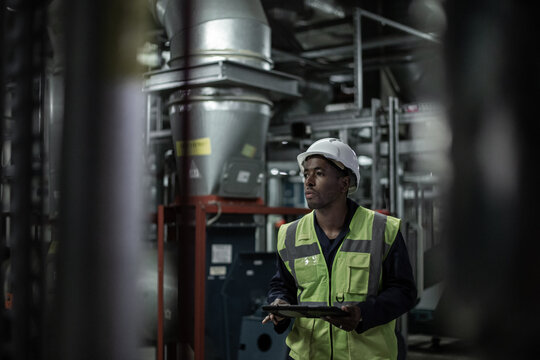 African american male engineer inspecting an industrial plant room
