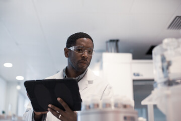 African American male scientist recording data on a digital tablet in a laboratory