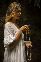 Caucasian woman keeping count during pray and meditation. Buddhist japa mala. Strands of gemstones beads. Religion concept. Buddhist jewelry. Woman wearing dress. Bali, Indonesia