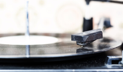 Fototapeta na wymiar the needle of a turntable playing the tracks of a black vinyl record.