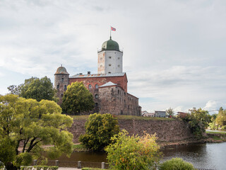 Fototapeta na wymiar Medieval Vyborg Castle is Swedish-built fortress. White tower of Saint Olav with flag. Historical and architectural landmark in Russia.