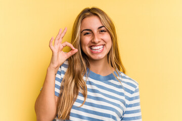 Young caucasian blonde woman isolated on yellow background  cheerful and confident showing ok gesture.