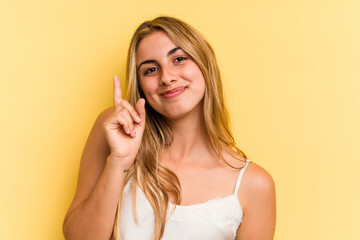 Young caucasian blonde woman isolated on yellow background  showing number one with finger.