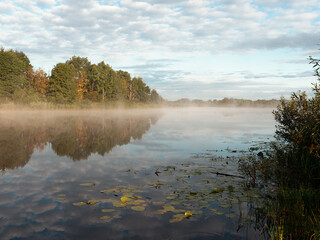 morning fog spreads over the smooth water of the river