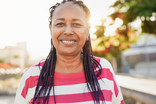 Mature african woman smiling on camera in the city with sunset in the background