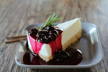 A Slice of Blueberry Cheesecake decorated by rosemary on top.