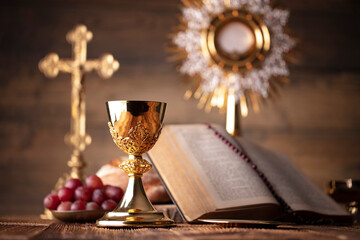 Catholic religion concept. Catholic symbols composition. The Cross, Holy Bible, rosary and golden chalice on the altar.