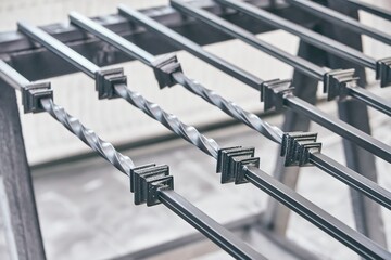 Welded metal balusters group dries after painting black color lying on trestles in light paint...