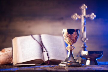 Catholic religion concept. Catholic symbols composition. The Cross, Holy Bible, rosary and golden chalice on the altar.