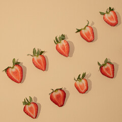 Symmetrically arranged tropical fruit and leaves, with half strawberry on beige background. Minimal flat lay