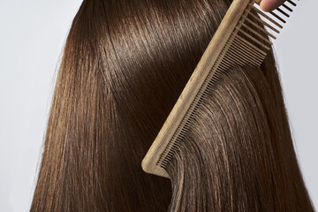 Combing healthy long straight female hair. Close up
