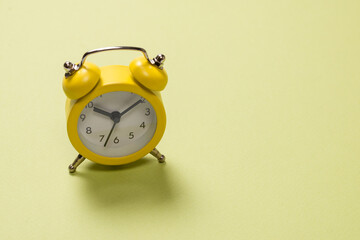 Yellow alarm clock on a green background. Time concept.