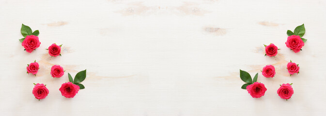 White wooden delicate background with pink roses and petals. Top view