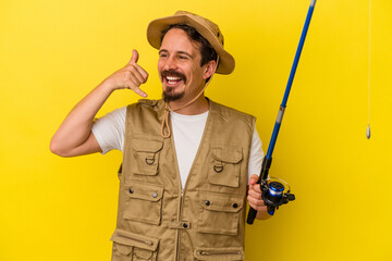 Young caucasian fisherman holding rod isolated on yellow background showing a mobile phone call gesture with fingers.