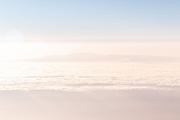 Misty Cloudscape. A mysterious island in pink and blue tones surrounded by the ocean and clouds. Fantastic dreamy picture