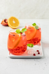 Summer mocktail, orange slises pomegranate seeds citrus drink in glasses. Space for text.