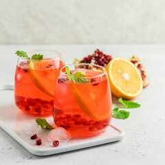 Refreshing summer iced mocktail, pomegranate citrus drink in glasses. Space for text.
