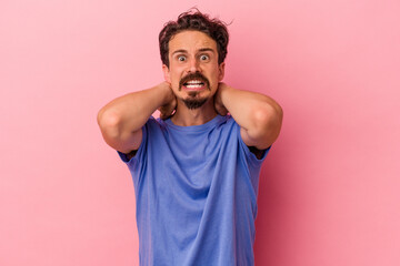 Young caucasian man isolated on pink background screaming with rage.