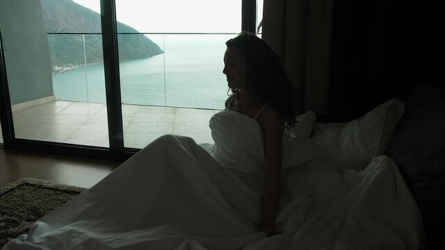woman gets out of bed in the morning. in a room with a sea view
