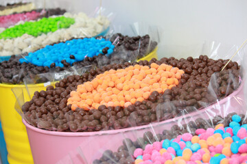 Different colorful candies in big jars or barrels in candy shop.