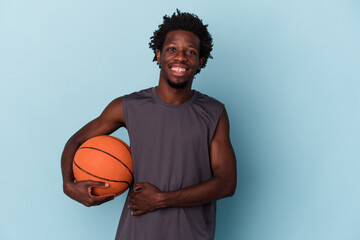 Young african american man playing basketball isolated on blue background laughing and having fun.
