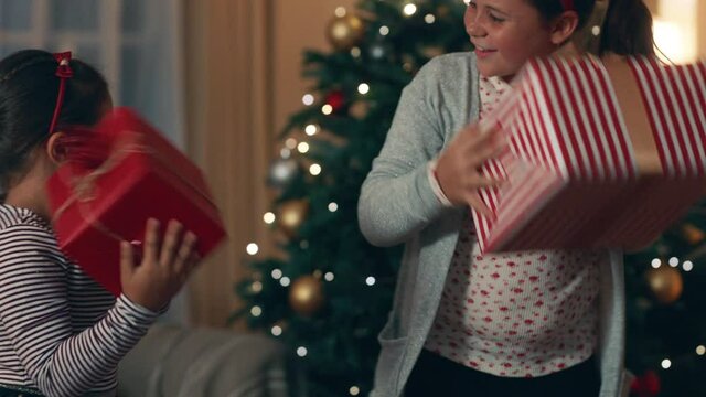 happy little girls excited to open gifts on christmas shaking presents curious children enjoying festive holiday celebration with family at home 4k