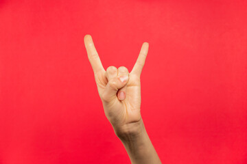 Mano rock, gesto o señal de rock, fondo rojo.
