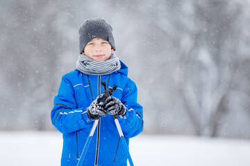 Close up portrait of small boy skiing in the winter park