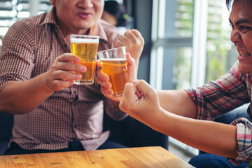 Successful businessman drinking beer, talking and smiling while celebrating at work.