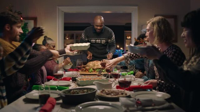 african american family christmas dinner man cutting turkey serving delicious meal at festive celebration sitting at table with friends enjoying delicious feast celebrating holiday at home 4k