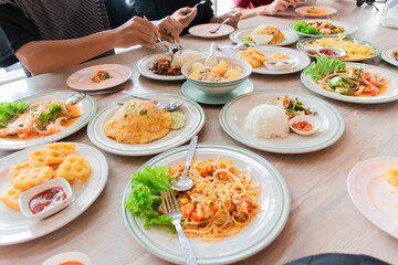 People are eating food, with a lot of food on the table.