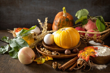 Seasonal food autumn baking background - ingredients for baking (pumpkin, apples, eggs, flour, sugar and spices) on a wooden table. Copy space.