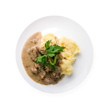Stroganoff with mashed potatoes on white plate isolated on white background top view