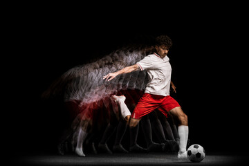 Young professional football player training alone isolated on black background. Stroboscope effect