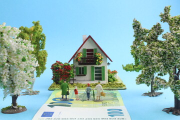 kleines Plastikhaus mit Figuren einer Familie im Vordergrund 