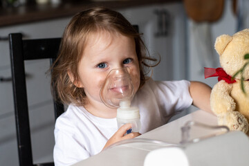 the child breathes through a nebulizer mask. treatment of cough in children. inhalation with a...