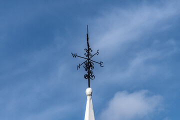 Wind vane with compass and blue sky background 