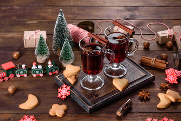 Christmas mulled red wine with spices and fruits on a dark table.