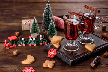 Christmas mulled red wine with spices and fruits on a dark table.
